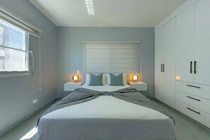 Une chambre à coucher avec un lit, des lampes de chevet, une fenêtre et une armoire.