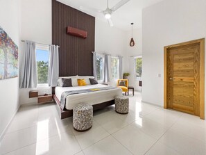 A modern bedroom with a large bed, two side tables, a wooden door, and a view of the outdoors. - Luxury BOSS Villa in Sosua Hispaniola (Sosúa)