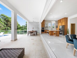 A modern kitchen with wooden cabinets, a central island, and a dining area with a table and chairs. - Luxury BOSS Villa in Sosua Hispaniola (Sosúa)