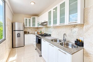 A modern kitchen with white cabinets, stainless steel appliances, and a granite countertop. - Hard Rock Central Suite,  Balcony, Parking (San Felipe de Puerto Plta)