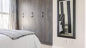 A bedroom with a bed, a wardrobe, a mirror, and a rug.