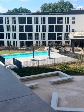 A modern building with a swimming pool, outdoor seating, and a landscaped area. - Rosebank Retreat, business or leisure (Johannesburg)