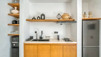 Une cuisine moderne avec des meubles en bois, un réfrigérateur en acier inoxydable, un four encastré, une machine à café et des objets décoratifs disposés sur des étagères.