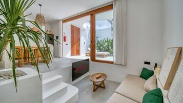 Un salon moderne avec un canapé, une petite table et un escalier menant à un balcon.
