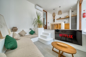 Een moderne woonkamer met een bank, een salontafel en een televisiescherm waarop 'NETFLIX' wordt getoond.