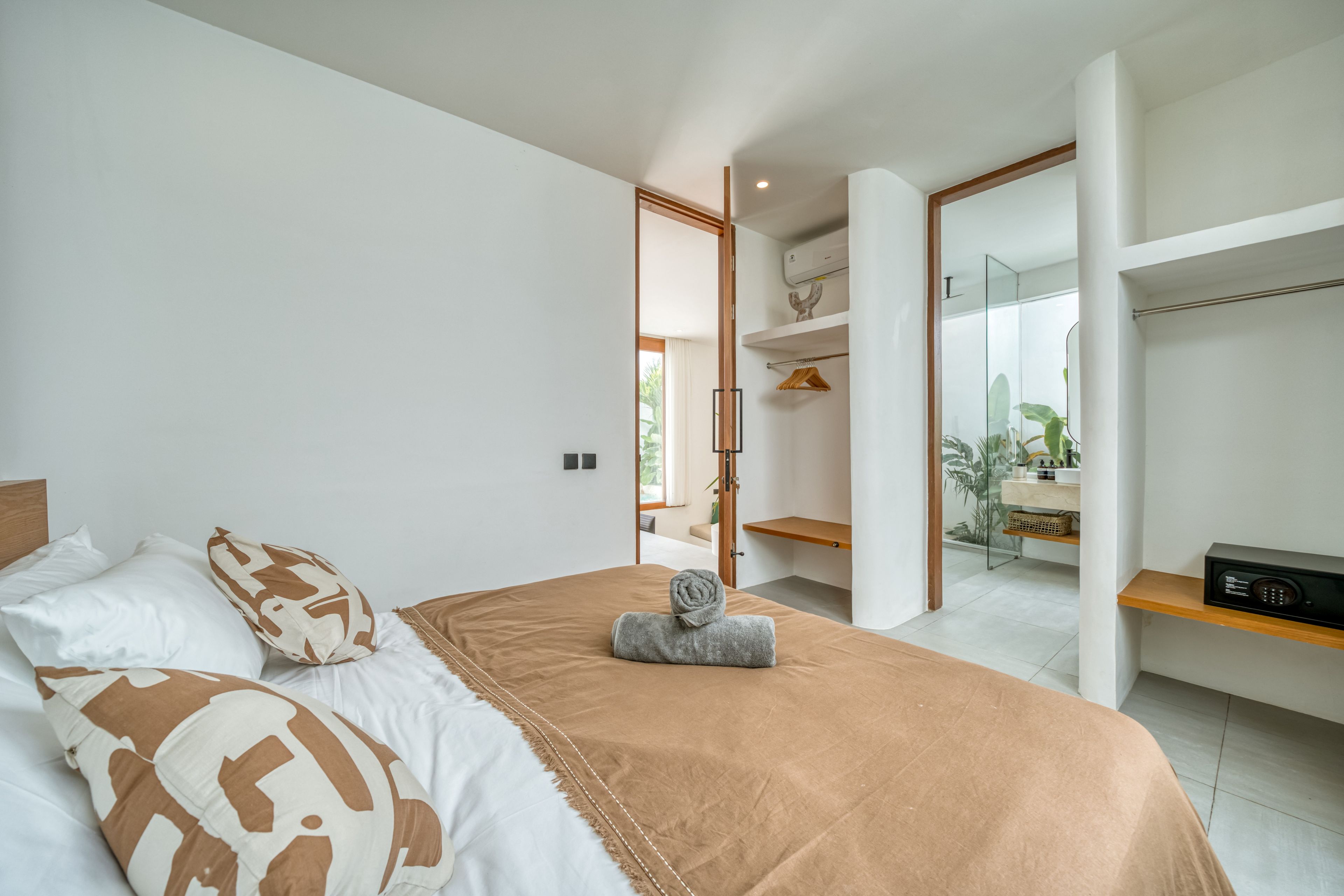 A modern bedroom with a bed, a bedside table, a mirror, and a wardrobe.