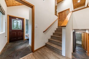A staircase with wooden steps and a handrail, leading to a landing with a door and a window. - Silver Moon on the North Shore by Tahoe Getaways - Pet-Friendly 3BR w Hot Tub, Foosball & Horeshoes (Tahoe Vista)