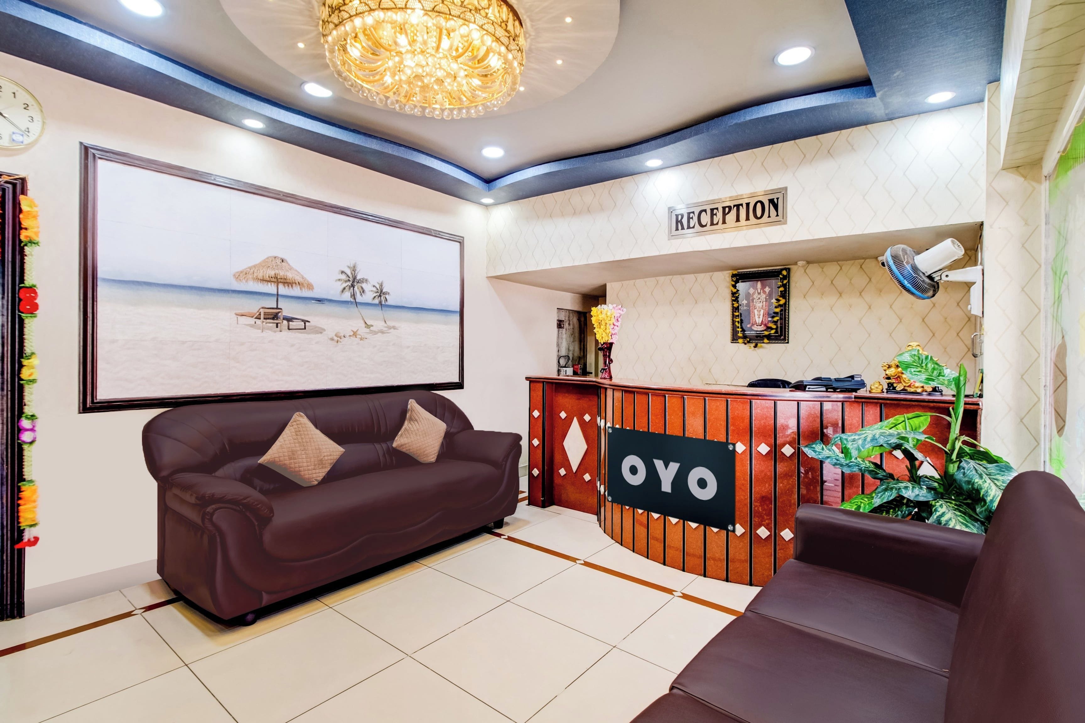 Ett receptionsområde med en receptionsdisk märkt med ”OYO”, en stor, inramad tavla med ett strandmotiv på väggen och en brun lädersoffa.