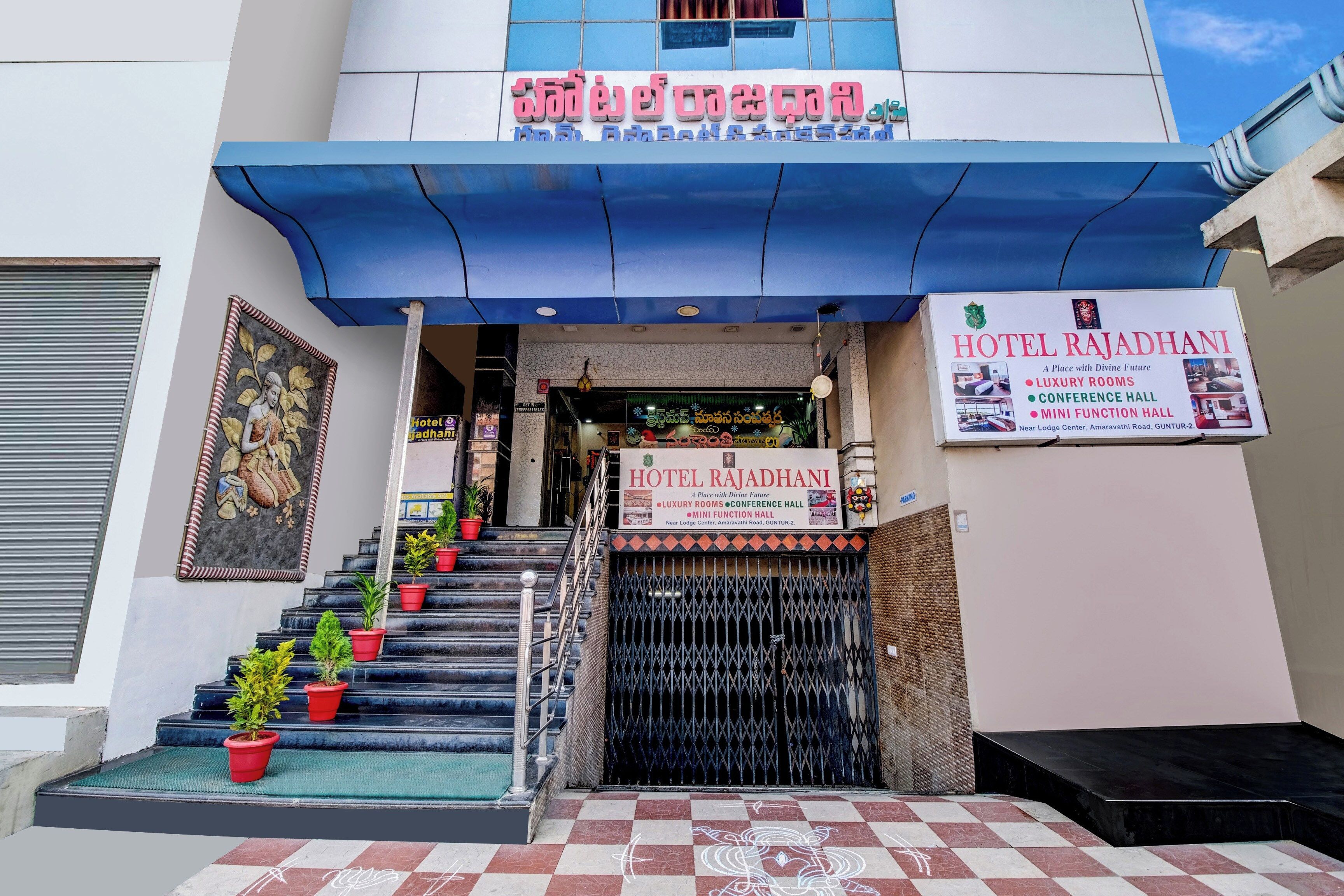 A hotel entrance with a staircase, a signboard, and a decorative mural.