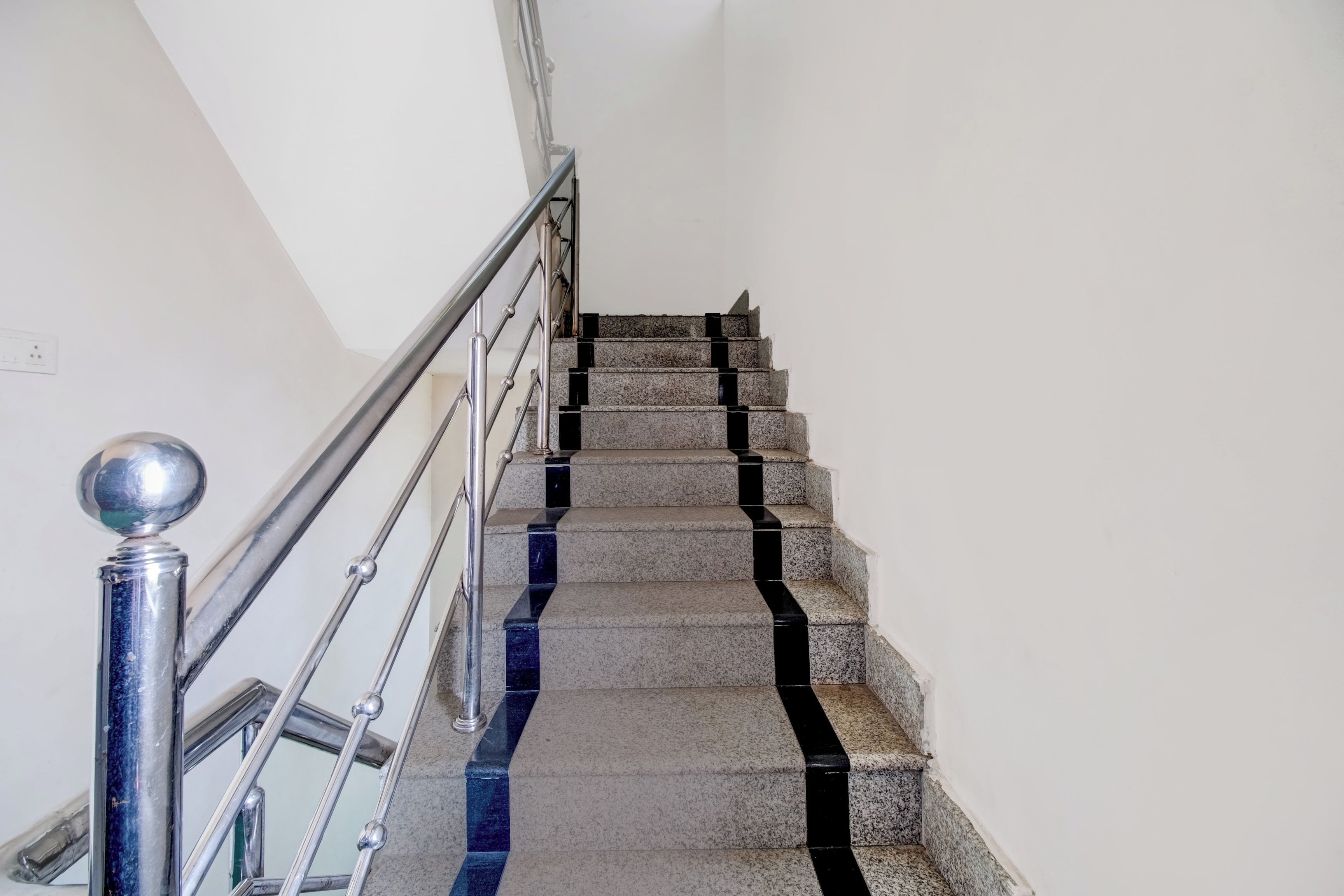 Una escalera con barandilla de metal y balaustrada de vidrio.