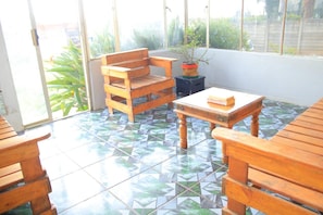 Eine sonnendurchflutete Terrasse mit Holzmöbeln und Fliesenboden.