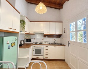 A kitchen with white cabinets, a stove, a microwave, and a refrigerator. - Artemis Sea Cottage - Near beach & airport by ΜΡS (Artemis)