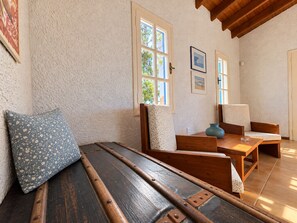 A room with a wooden bench, a table, and chairs. There are windows with white frames and a door. - Artemis Sea Cottage - Near beach & airport by ΜΡS (Artemis)