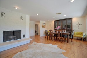 A dining area with a wooden table, chairs, and a sofa. There is a fireplace with a white rug in front. - 2 Boat Docks! Marble Falls Lake Retreat (Marble Falls)