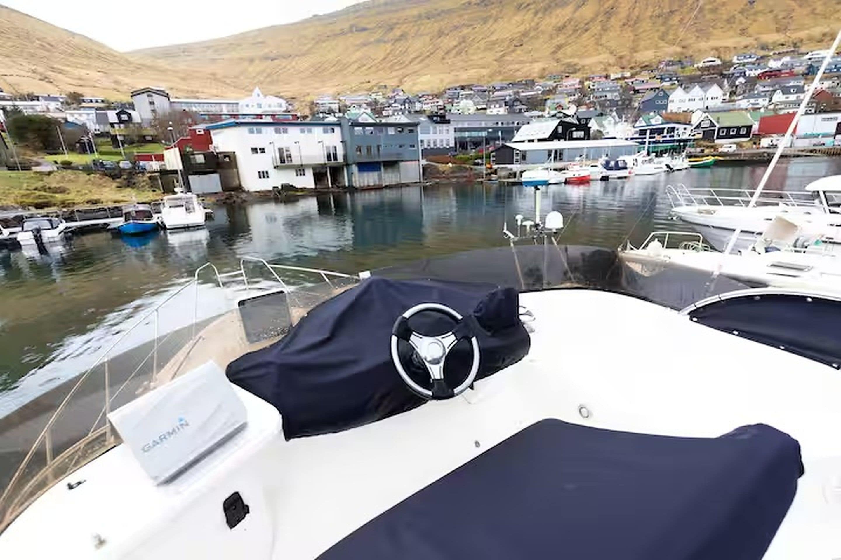Eine Marina mit vertäuten Booten, eine Stadt im Hintergrund und ein Hügel.