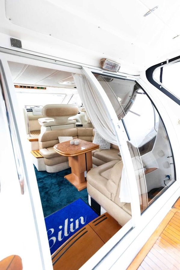 A yacht interior with a seating area, a small table, and a blue area rug.