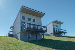 Two modern, multi-story buildings with balconies, situated on a grassy hill. - 1 Mi to Floyd Country Store: Cozy Mtn Cottage (Floyd)