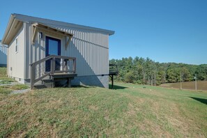 En enplansbyggnad med en blå dörr och en liten veranda med ett metallräcke.