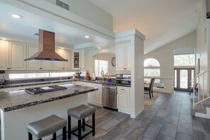 A spacious kitchen with a large island, built-in appliances, and a view to the dining area. - Private Pool & Patio: Modern Henderson Home (Henderson)
