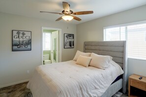 A bedroom with a bed, a ceiling fan, a nightstand, and two framed pictures on the wall. - Private Pool & Patio: Modern Henderson Home (Henderson)