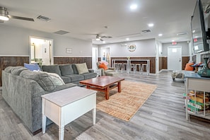 A modern living room with a sectional sofa, a coffee table, and a small white table. There is a fireplace with a mantel and a clock on the wall. - Riverside Retreat -Horse Creel Retreat Arcadia (Arcadia)