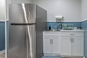 A kitchen with a stainless steel refrigerator, a sink with a faucet, and white cabinets. - Riverside Retreat -Horse Creel Retreat Arcadia (Arcadia)