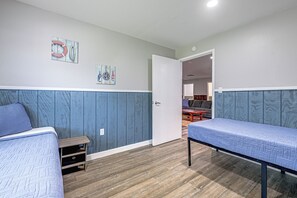 Ett rum med två sängar, ett litet bord och en dörr som leder till ett annat rum.