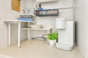 A compact kitchen area with a coffee maker, a small plant, and neatly arranged dishes and utensils. - Castaway Creek Cabin - Horse Creek Retreat Arcadia (Arcadia)