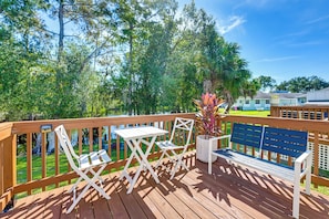 A wooden deck with a white table and chairs, a blue bench, and a potted plant. - Castaway Creek Cabin - Horse Creek Retreat Arcadia (Arcadia)