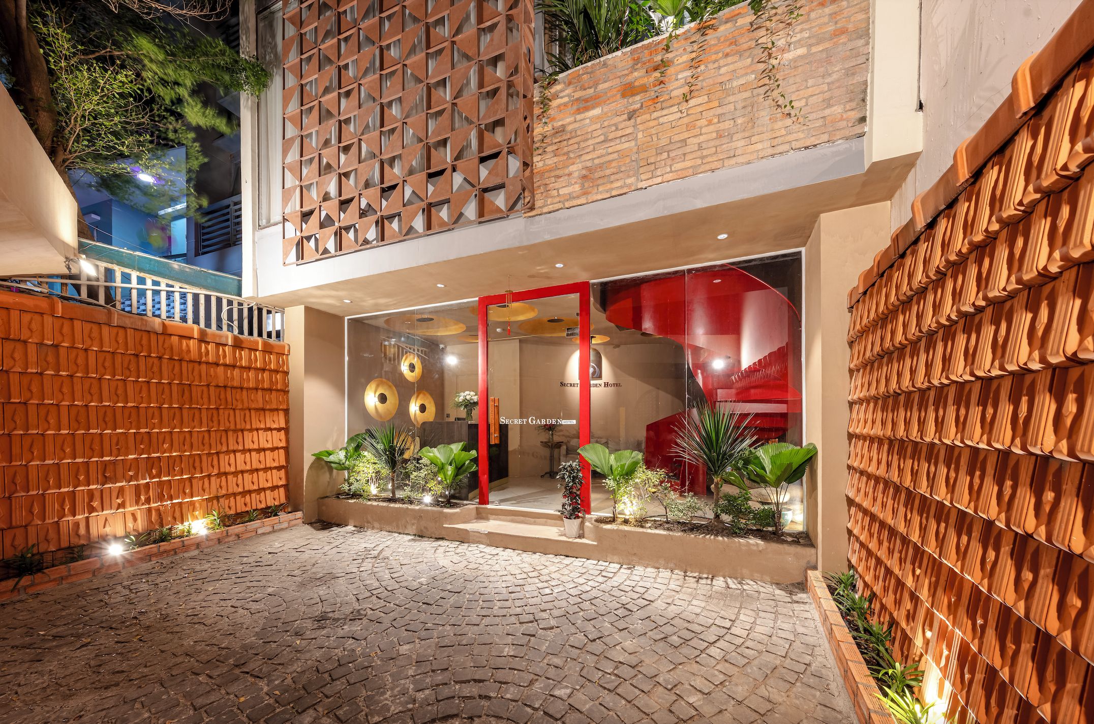 Ein Hotel mit Backsteinfassade, einer rot umrahmten Glasdoor und einer Backsteinwand mit geometrischem Muster.