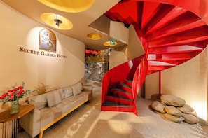 Un interior moderno con una escalera de caracol, un sofá y un cartel en la pared del Secret Garden Hotel.