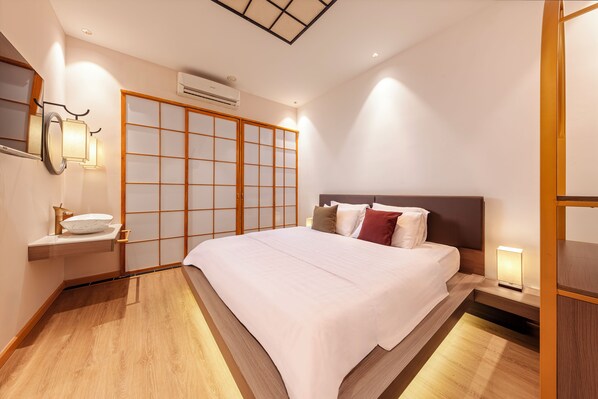 Una habitación de hotel con cama, mesita de noche, lámpara y un panel corredizo estilo shoji.