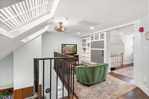 A modern interior with a staircase, a television, and a bookshelf. - Historic Old Town Retreat | Steps to King Street (Alexandria)