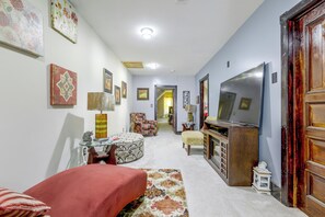 A hallway with a television, a sofa, a rug, and various framed pictures on the walls. - Extended Springfield Stay Near Downtown & MGM (Springfield)