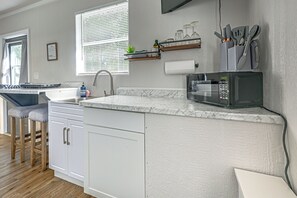 A kitchen with a built-in microwave, a sink, and bar stools. - Boathouse Cabin at Horse Creek Retreat (Arcadia)