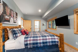 Una camera da letto con un letto, una testiera in legno, una TV a parete e una finestra con vista.