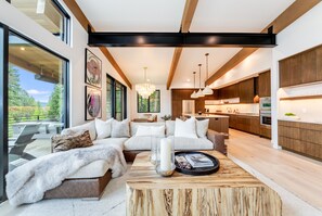 Una sala de estar moderna con un sofá seccional, una mesa de centro y vista a la cocina.
