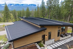 A modern house with a sloped roof, wooden siding, and a stone foundation. - New! Family Ski Getaway with Hot Tub, Chef's Kitchen & Fireside Deck, Monthly Stays (Whitefish)