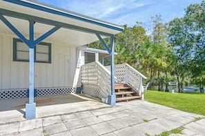 A white building with a blue porch and a staircase leading to a covered entrance. - Cozy Creekside Cottage at Horse Creek Retreat (Arcadia)