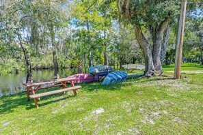 A picnic table and a canoe near a calm lake surrounded by trees. - Cozy Creekside Cottage at Horse Creek Retreat (Arcadia)