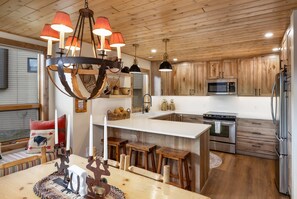 A modern kitchen with wooden cabinets, stainless steel appliances, and a central island with stools. - New Listing! Ski-In/Ski-Out with Indoor Hot Tub in Big Sky (Big Sky)