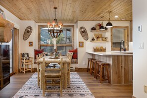 A rustic interior with a wooden dining table, chairs, and a chandelier. - New Listing! Ski-In/Ski-Out with Indoor Hot Tub in Big Sky (Big Sky)