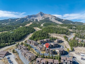 A residential area with multi-story buildings, roads, and a mountain in the background. - New Listing! Ski-In/Ski-Out with Indoor Hot Tub in Big Sky (Big Sky)