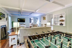 A room with a foosball table, a fireplace, a television, and a seating area with a sofa and armchairs. - 3 Mi to Wadsworth Falls! Retreat w/ Backyard Oasis (Middletown)