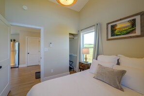 A bedroom with a bed, a nightstand, a window with curtains, a painting on the wall, and a hallway leading to a door. - Near Trails & Live Music! Quiet Floyd Gem w/ Views (Floyd)