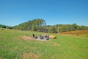 An outdoor seating area with Adirondack chairs and a fire pit in a grassy field. - Near Trails & Live Music! Quiet Floyd Gem w/ Views (Floyd)