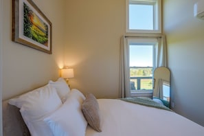 A hotel room with a bed, a nightstand, a lamp, a painting, and a window with a view. - Near Trails & Live Music! Quiet Floyd Gem w/ Views (Floyd)