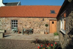 A stone building with a tiled roof, a wooden door, and a small window. - Holiday accommodation Byre (Drem)