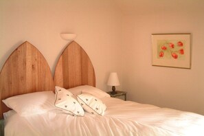 A bed with a wooden headboard, two pillows, a bedside lamp, and a framed picture on the wall. - Holiday accommodation Byre (Drem)