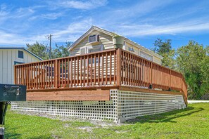 Ein Bungalowmobilheim mit einer Holzterrasse und einem weißen Zaun.